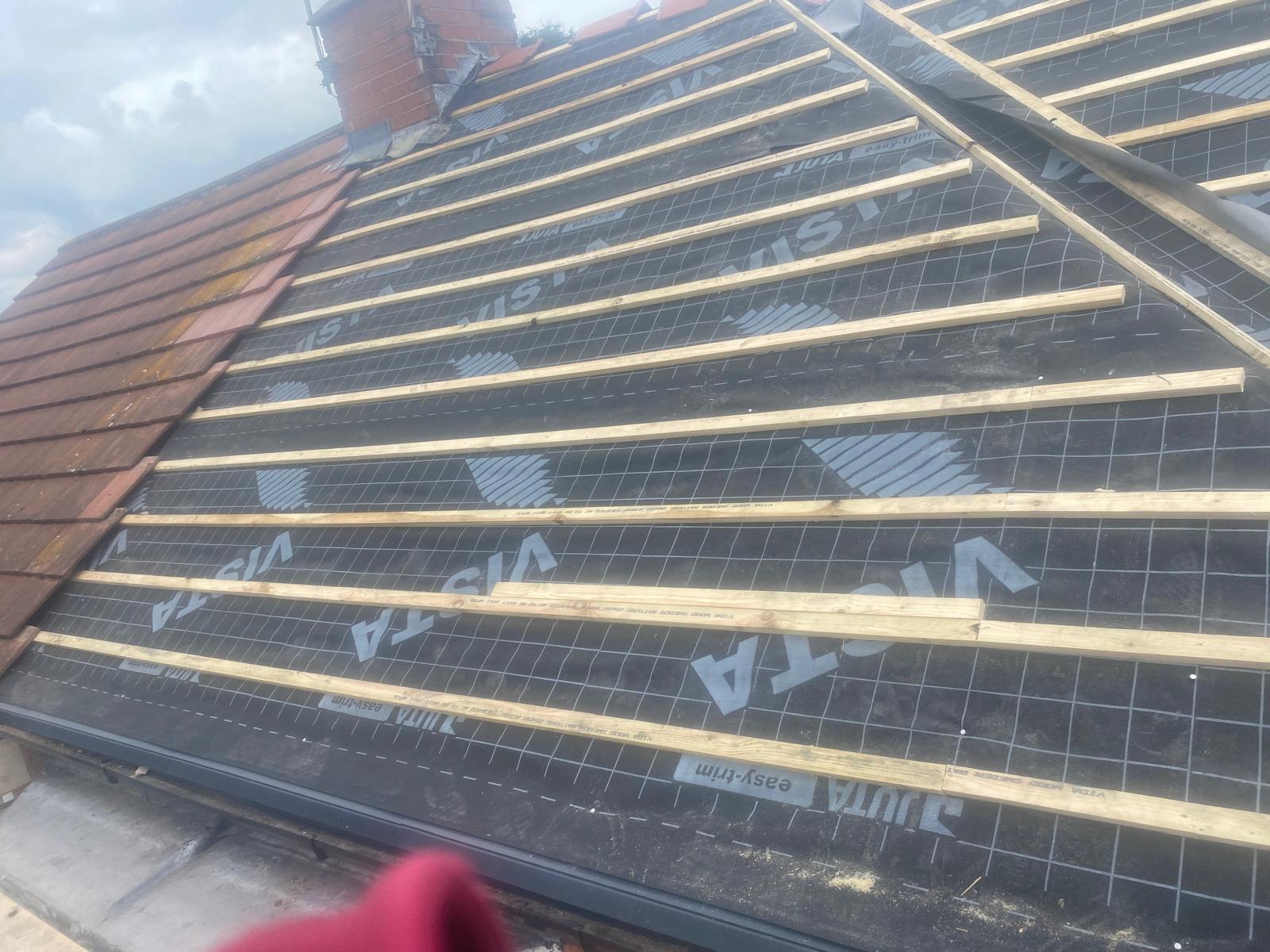 Roof mid-install with exposed battens and slates being laid
