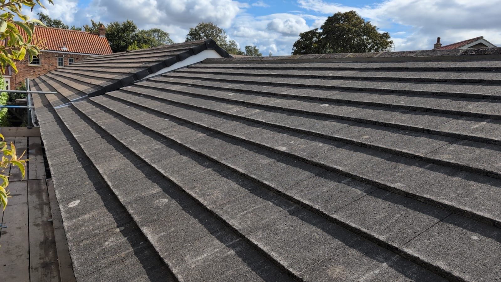Repaired grey tile pitched roof with new ridge capping