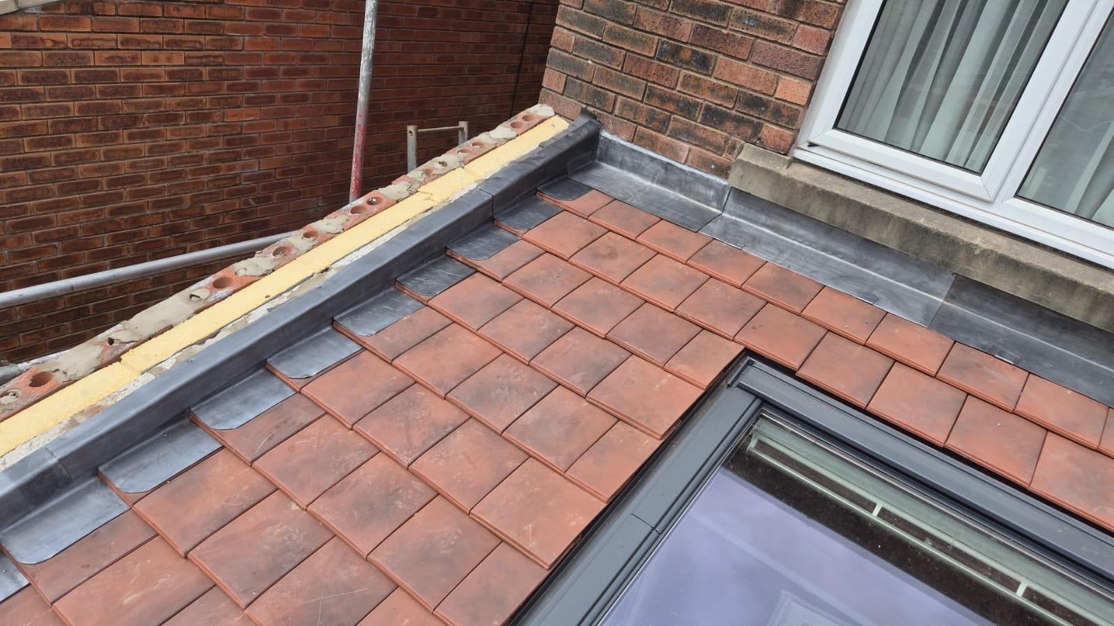 A clay tile reroof dressed in with lead against a brick wall on a York home
