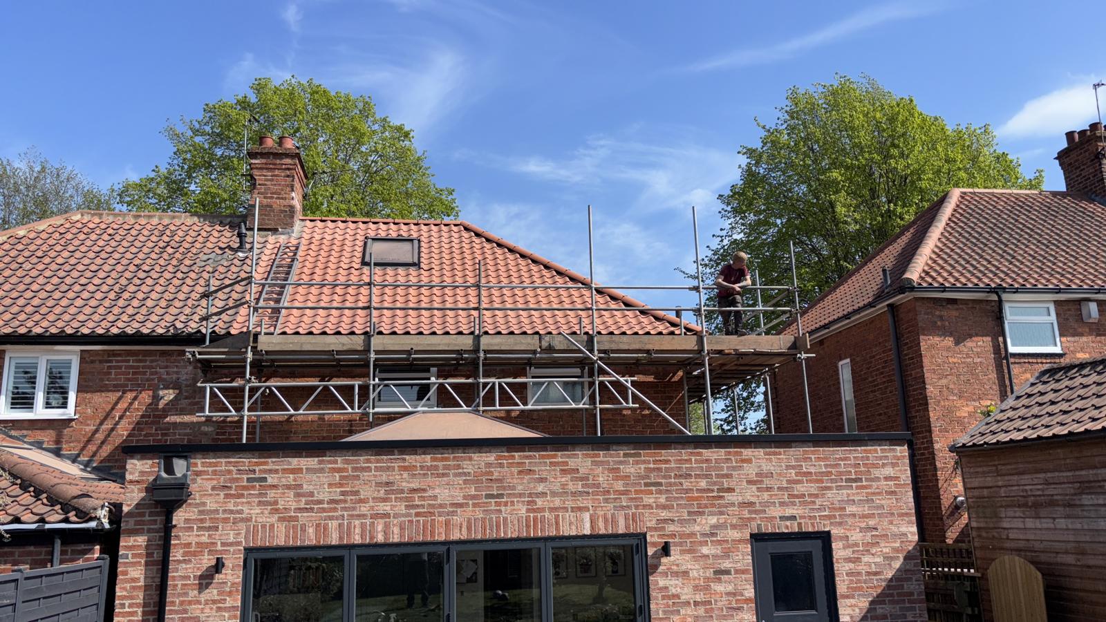 A rolling orange-red clay pantile roof on a house near York, blue sky behind