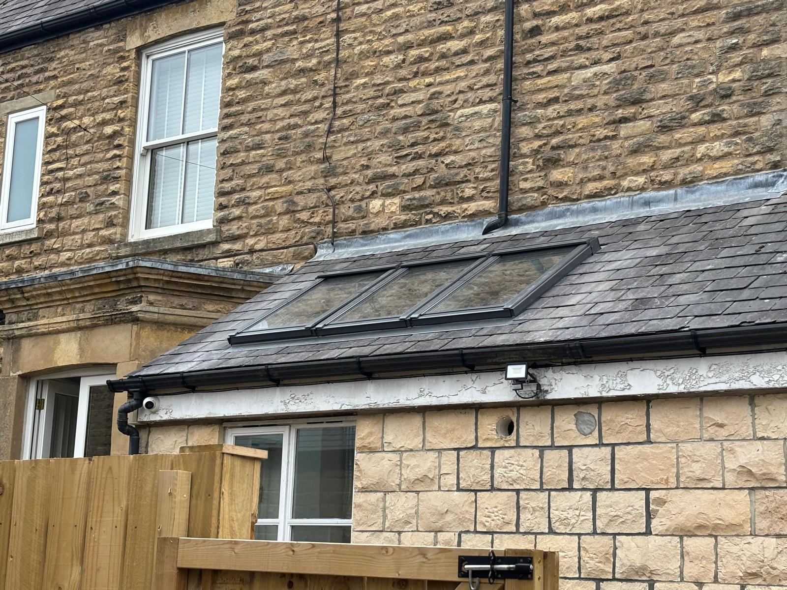 New slate roof with conservation roof windows against a stone house in York