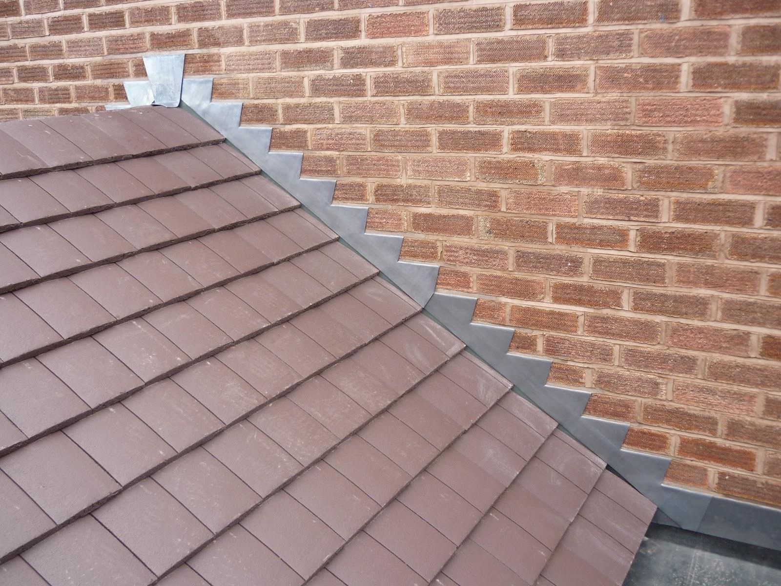 Stepped lead flashing dressed between a tiled roof and a red-brick wall